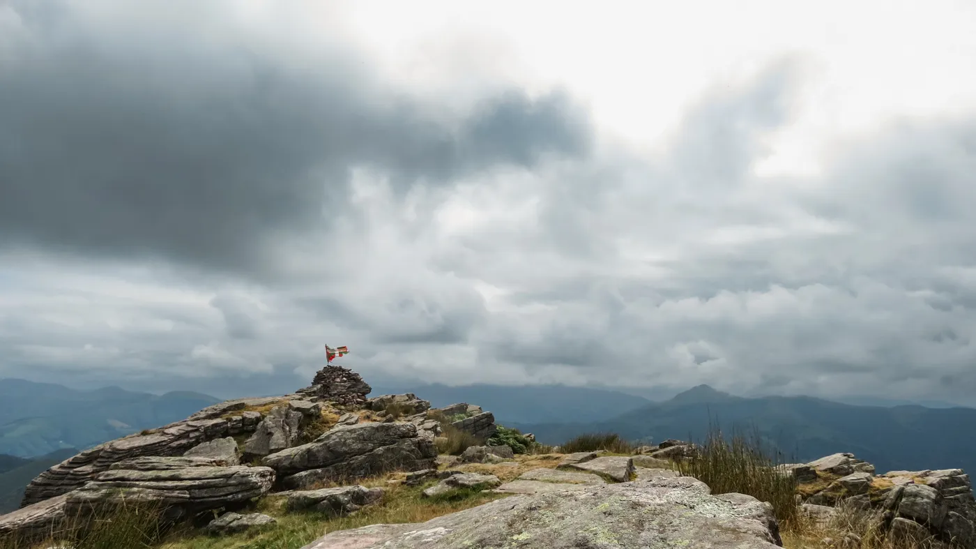 Journée nuageuse sur un sommet de Navarre dévoilant un terrain rocheux et un horizon lointain.
