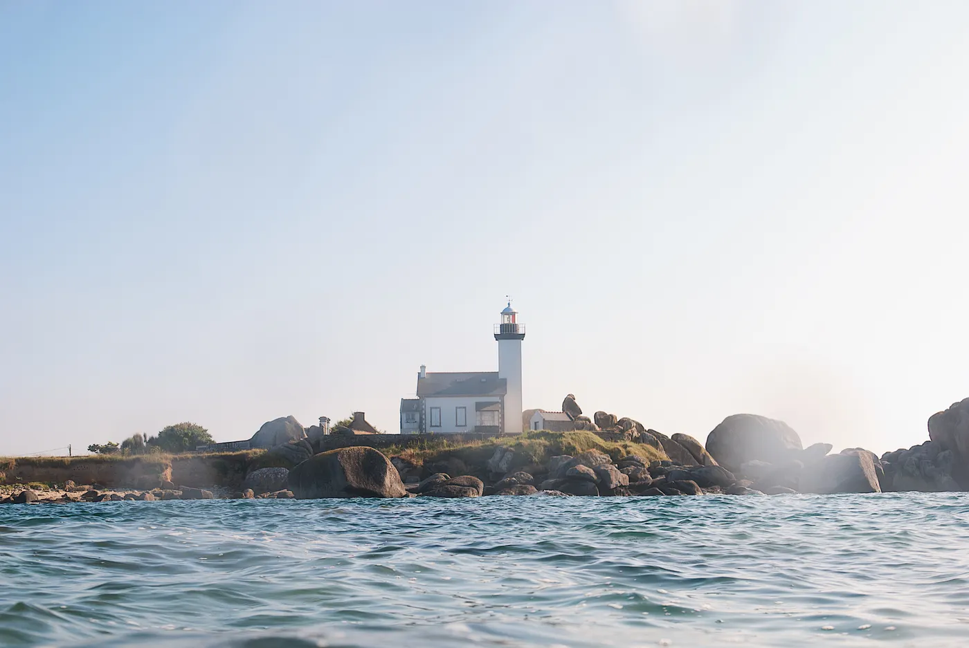 Magnifique vue d'un phare sur la côte rocheuse de Bretagne, en France, avec les vagues calmes de l'océan.